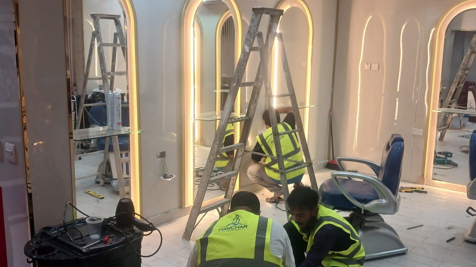 Arched mirror stations with gold trim being installed at the Al Massa beauty center in Doha
