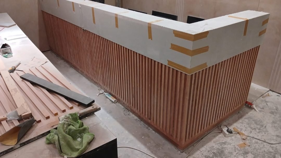 Timber slat reception counter being built during the gym fit-out at Edge Iconic, Doha
