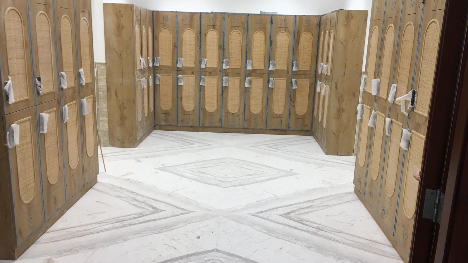 Stone-clad changing area with timber lockers at Marriott Marquis City Center Doha